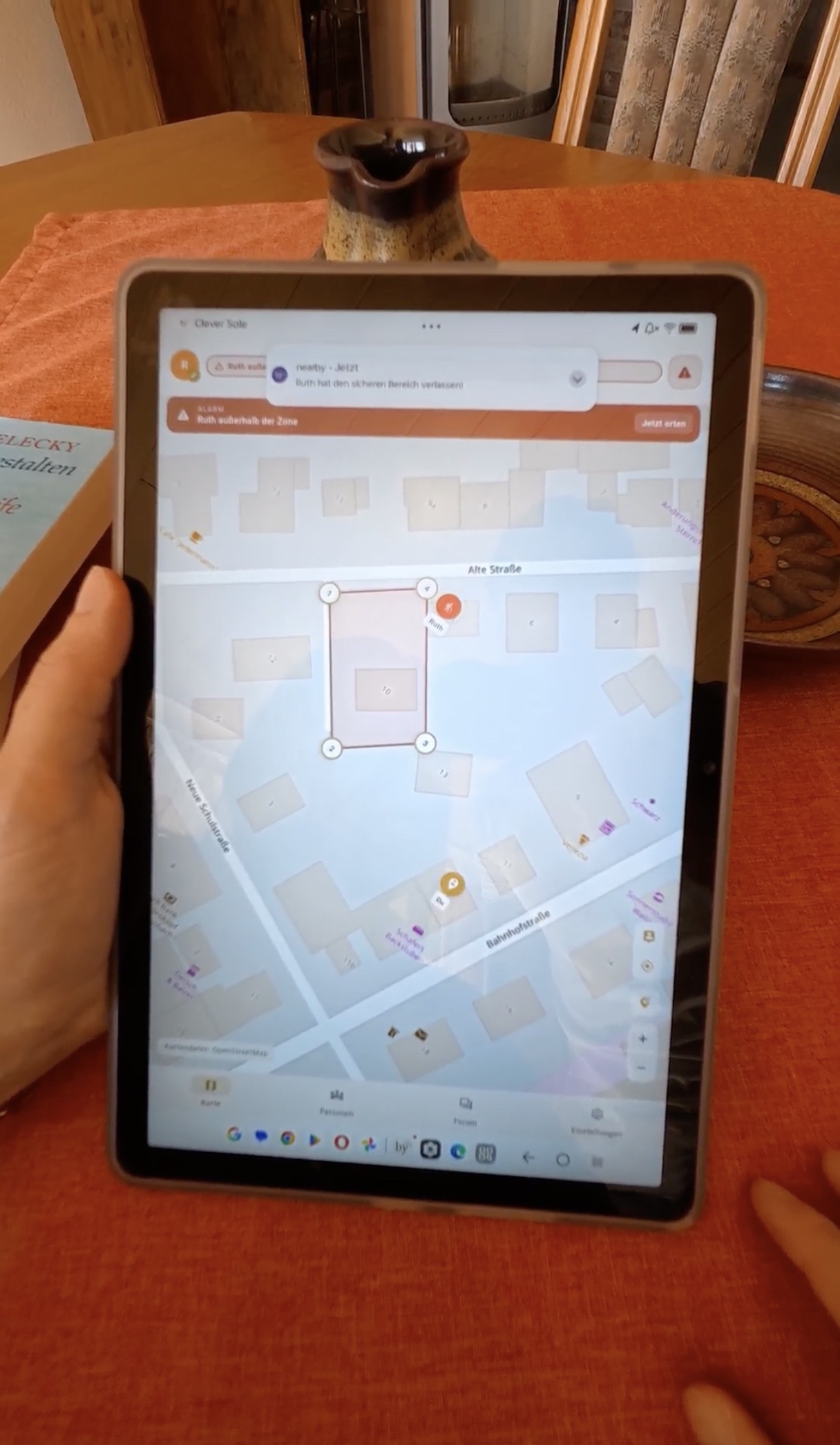 Auf einem Tablet meldet die nearby App, dass Ruth den sicheren Bereich verlassen hat.