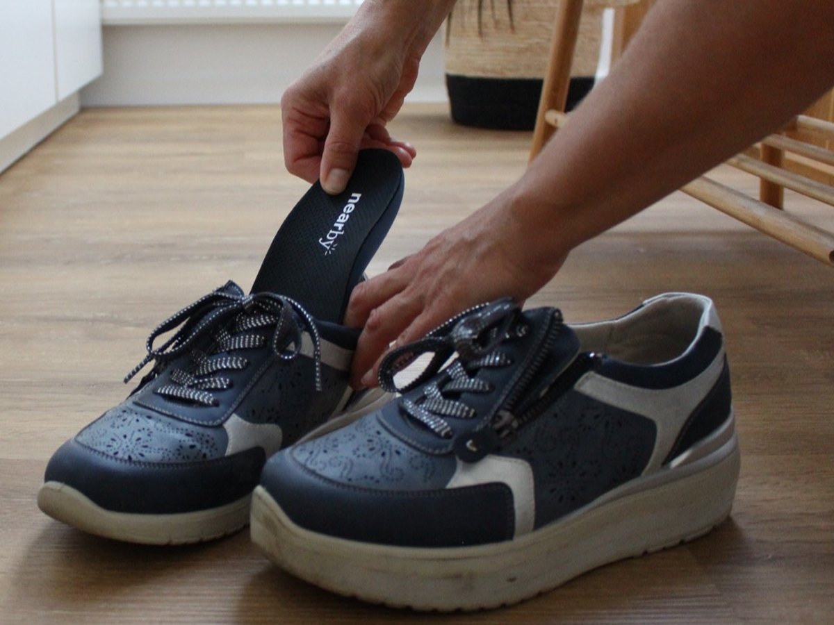 Eine Hand legt eine der nearby GPS-Einlegesohlen in einen Schuh.